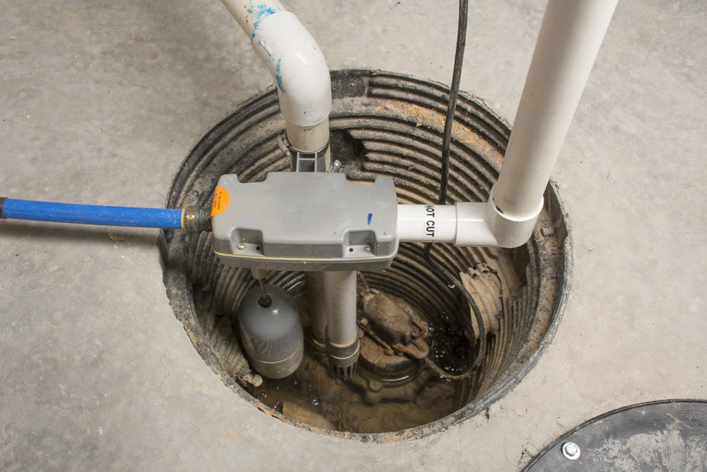 A sump pump is expertly installed in a basement pit, featuring PVC pipes for water discharge and a float switch for activation. The concrete surroundings are clean and well-maintained. For reliable plumbing services in Cook County, IL, ensure your setup meets top standards.