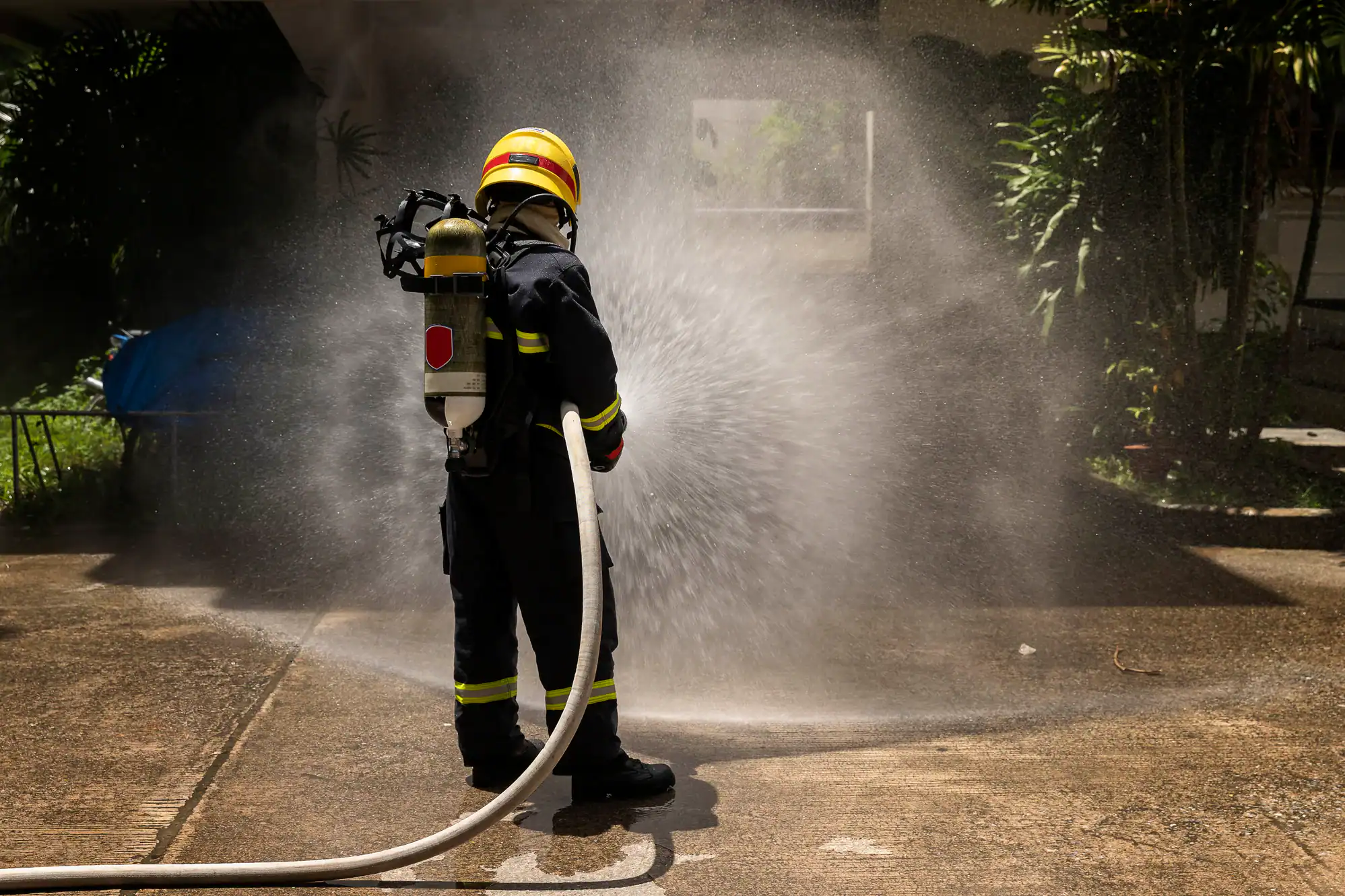 A firefighter in full gear aims a powerful hose at a blaze, spraying a focused stream of water during an emergency in Chicago