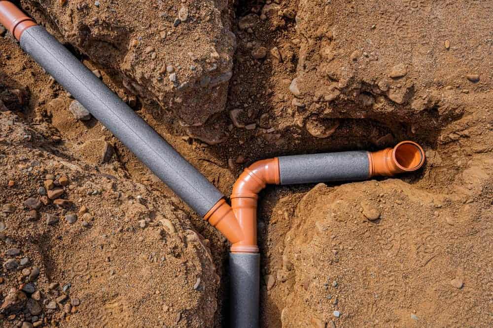 Workers weave multiple sewer pipes into a single line at a Chicago, IL construction site; high-angle urban view